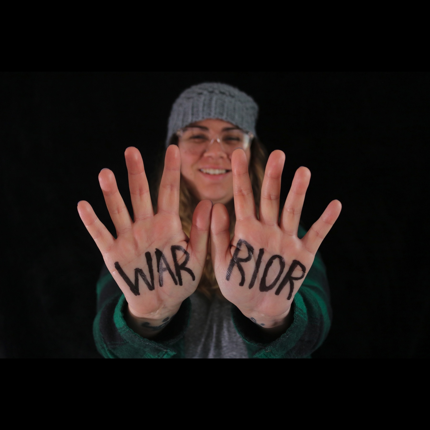 Alyssa Marie Williams holding up her hands with WARRIOR written across her palms.